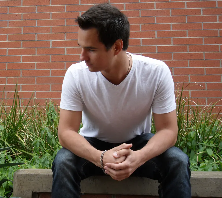 Roman sitting on a stone ledge in front of a red brick wall, looking off to the side
